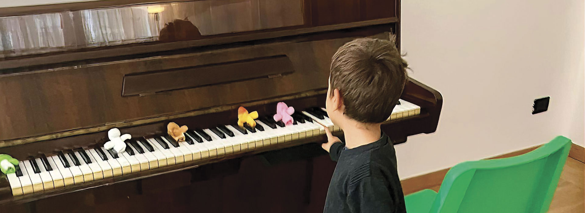 Un bambino di spalle davanti a un pianoforte durante un percorso di musicoterapia per esprimere le emozioni, Associazione CAF.